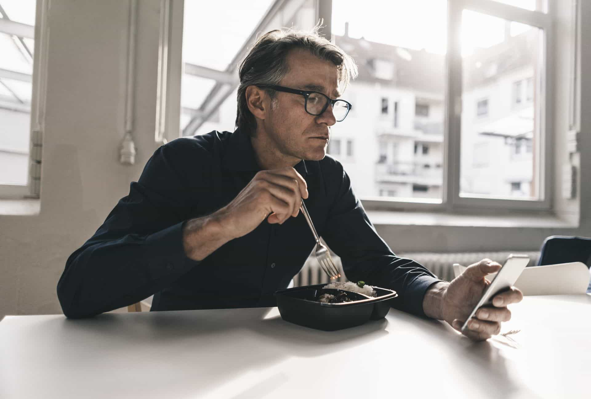 Hombre comiendo viendo el teléfono